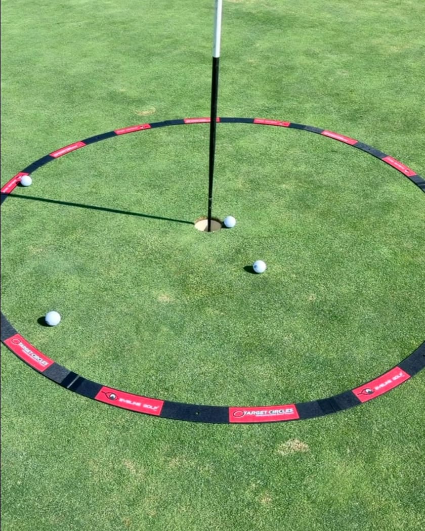 Practice green with a target circle laid around the hole; some balls stopped inside it, some outside.